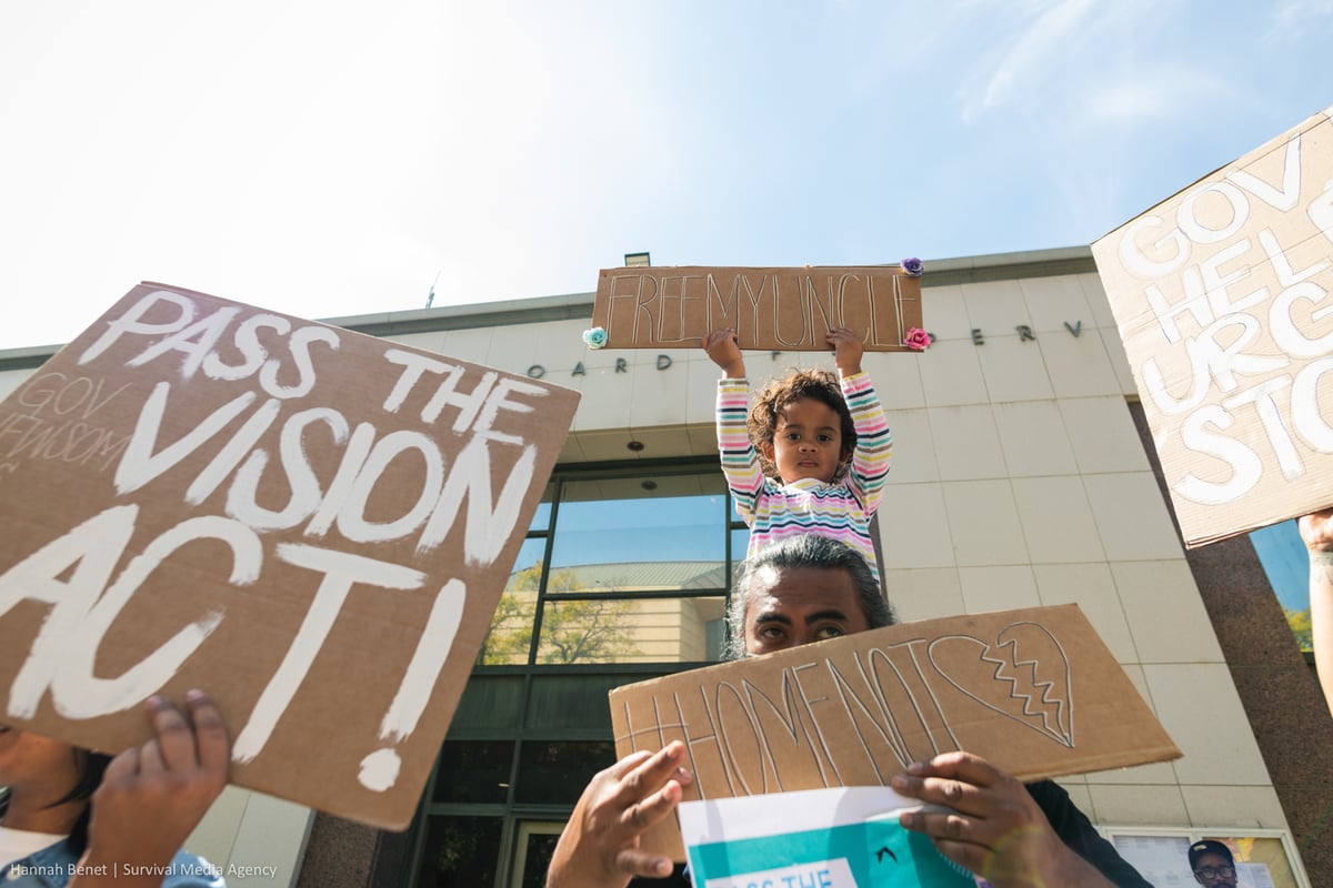 Vithea's toddler niece sits on the shoulder of a family member and holds up a sign that reads "free my uncle"