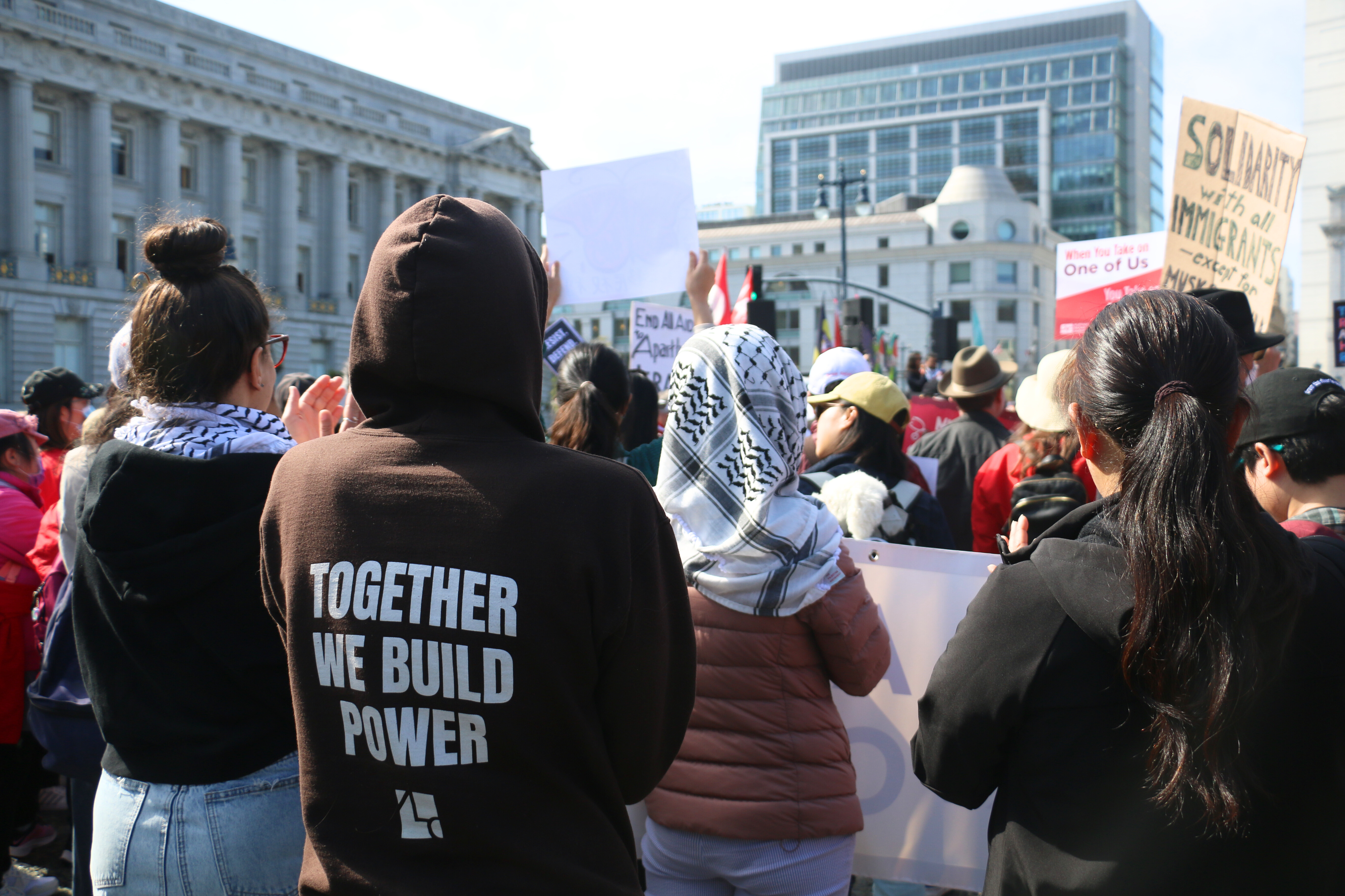 ALC staff stand with their backs turned to the camera at the 2025 May Day rally in San Francisco.