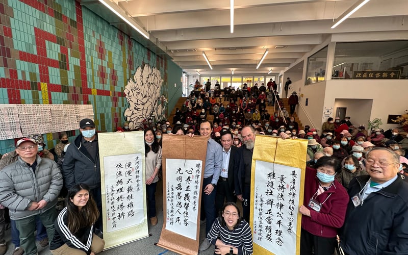 San Francisco Chinatown residents, Community Tenants Association, and staff from the Asian Law Caucus, Legal Assistance to the Elderly, and Ropes & Gray pose together for a photo celebrating the 2022 Valstock settlement. The group stands behind scrolls of Chinese calligraphy honoring the legal team,