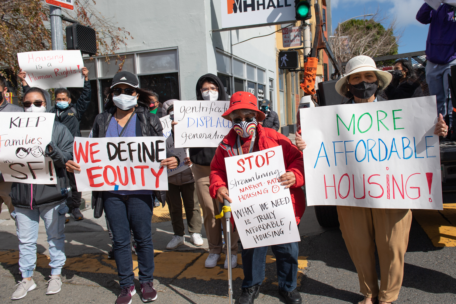 Protesters holding up signs about housing at a crosswalk in San Francisco.