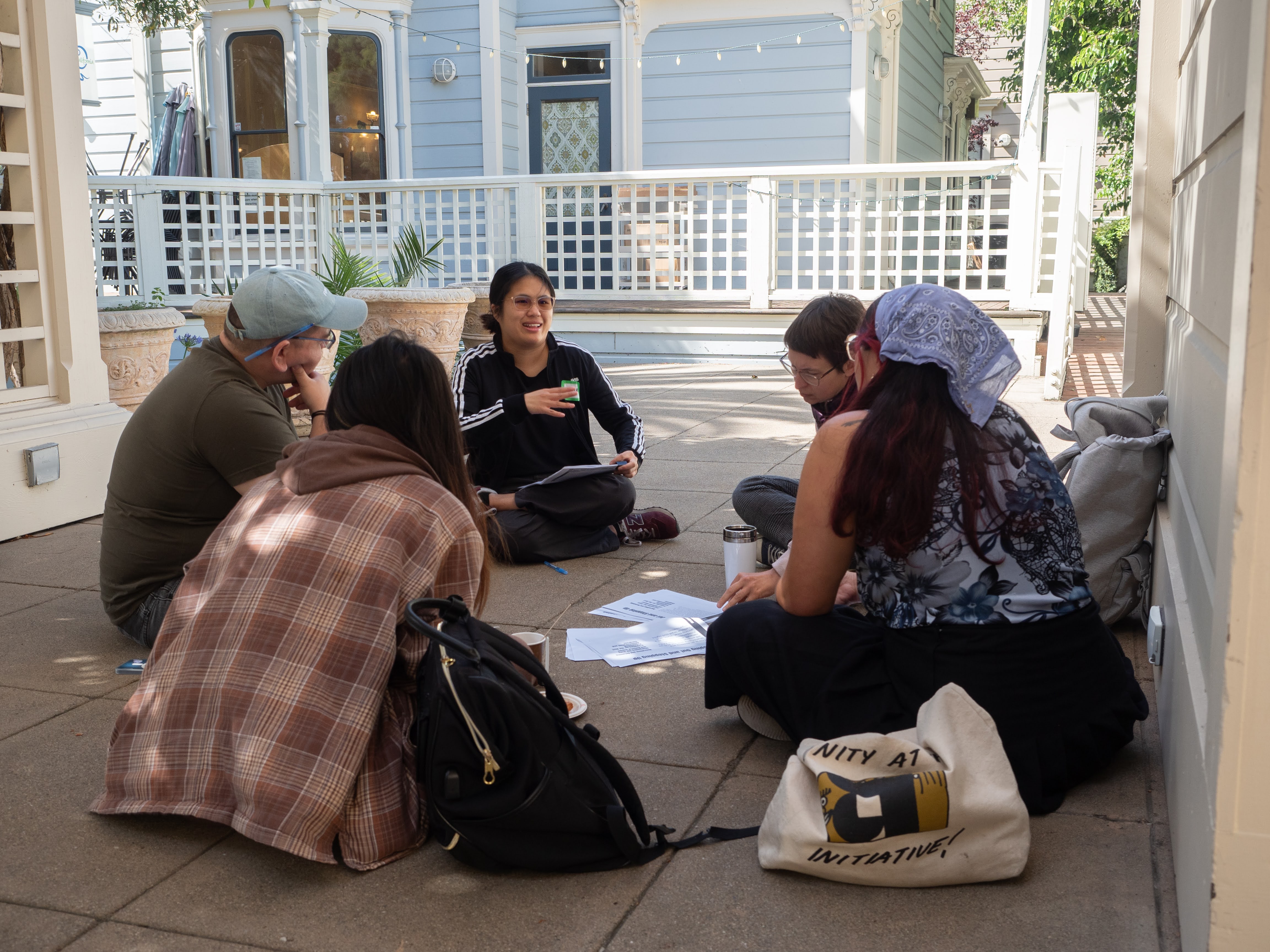 ALC's housing rights team sitting in a circle on the ground in a patio setting.