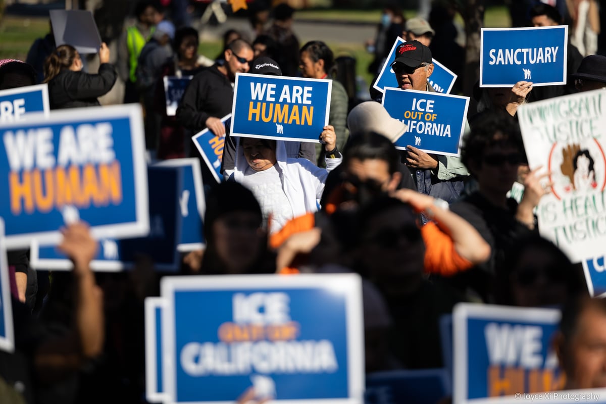Large gathering of people holding up signs, picture focuses on one that says 'We Are Human'.
