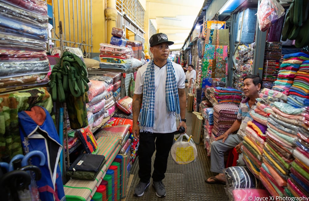 Pheoun walks through a textile bazaar in Cambodia.