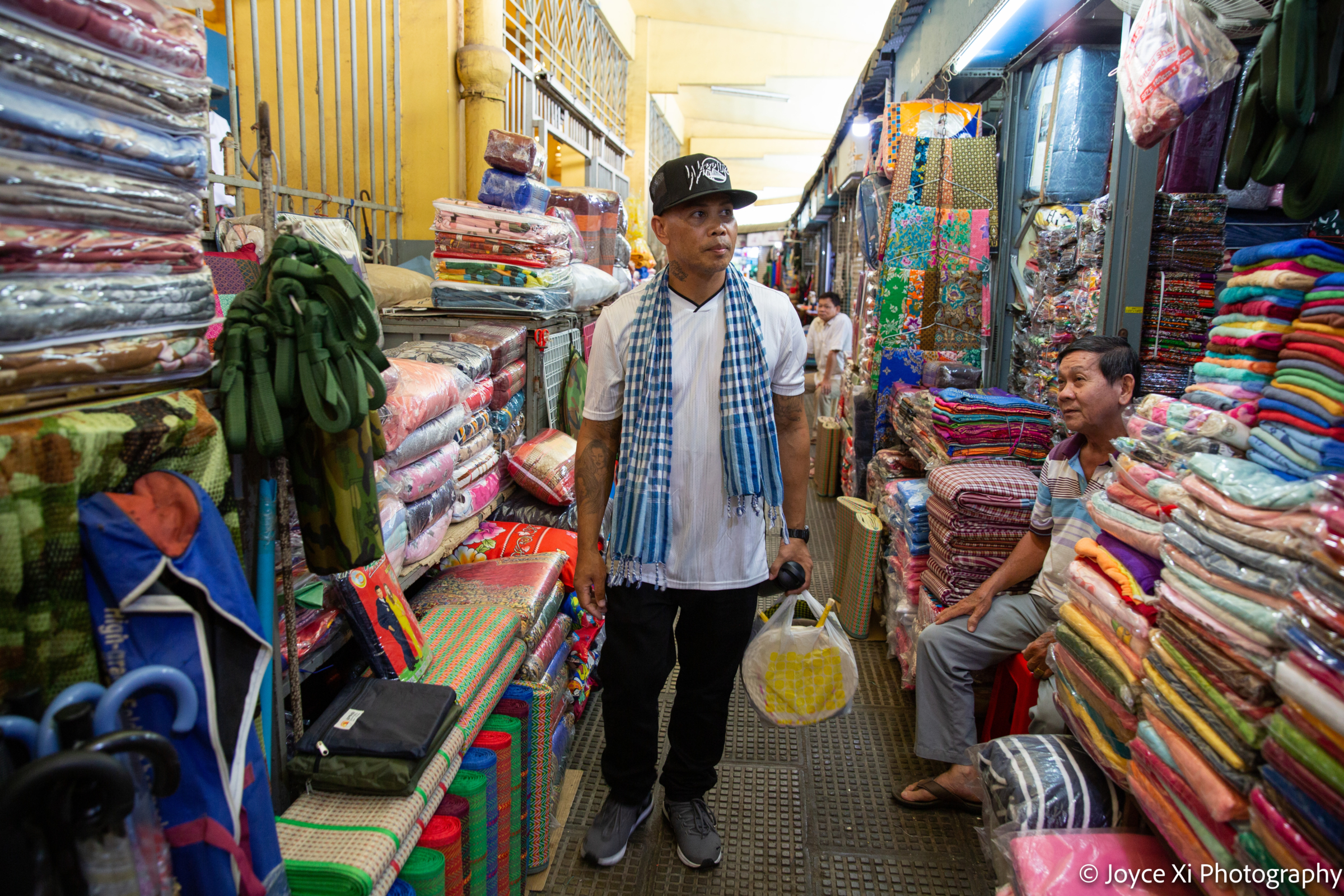 Pheoun walks through a textile bazaar in Cambodia.