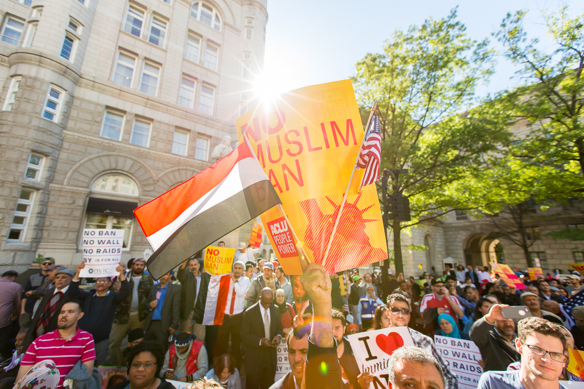 A large group of protestors holding up a yellow and red sign that reads "No Muslim Ban Ever."