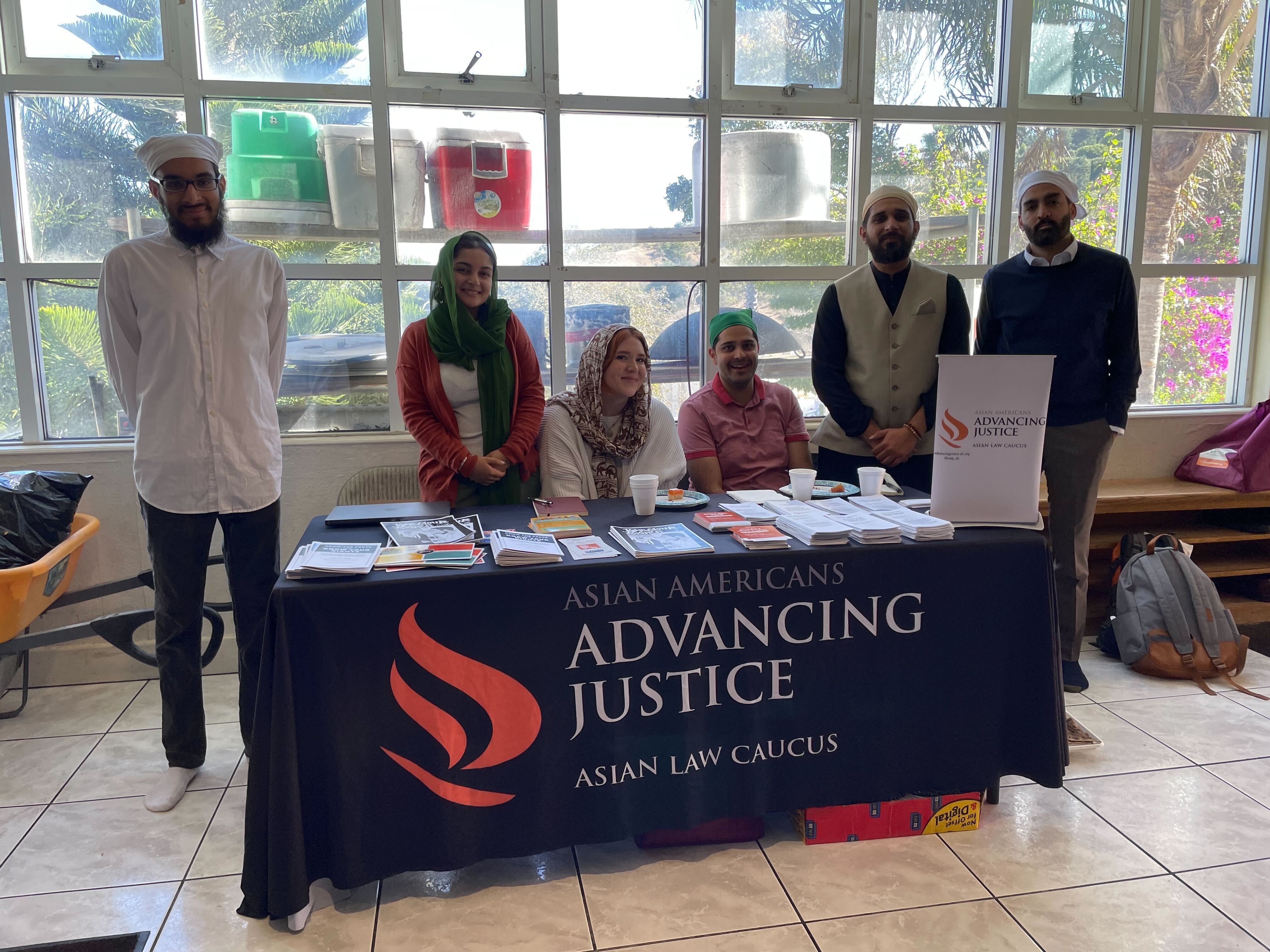 6 ALC staff members at their outreach table in a local Gurdwara, offering print resources.