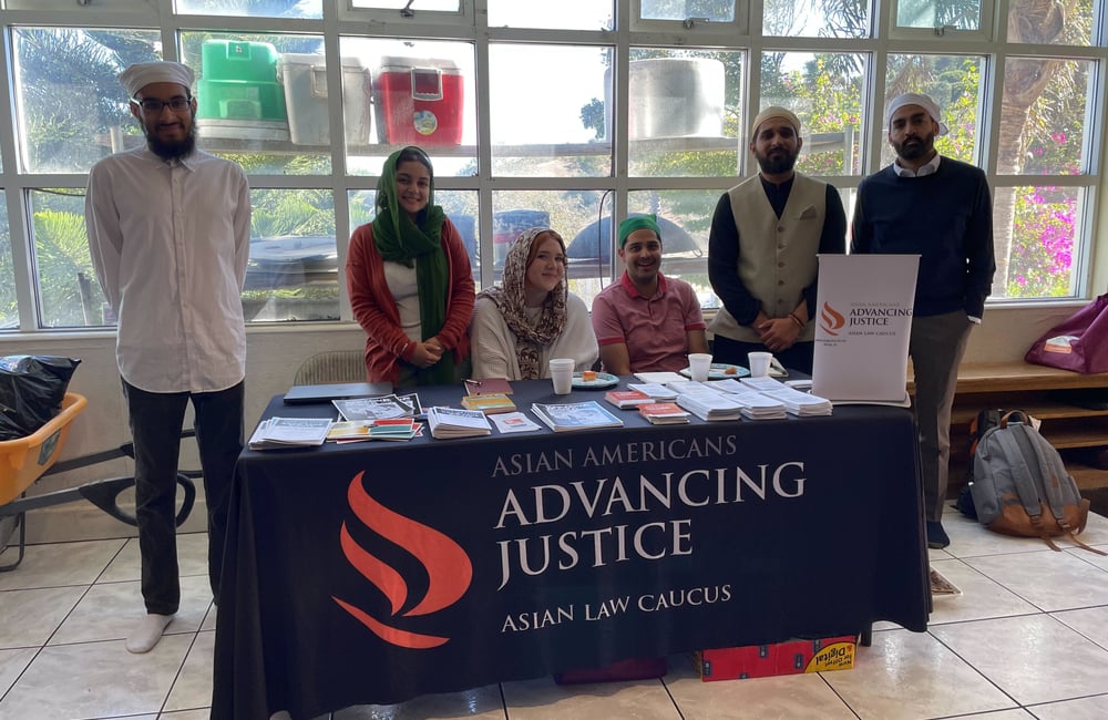 6 ALC staff members at their outreach table in a local Gurdwara, offering print resources.