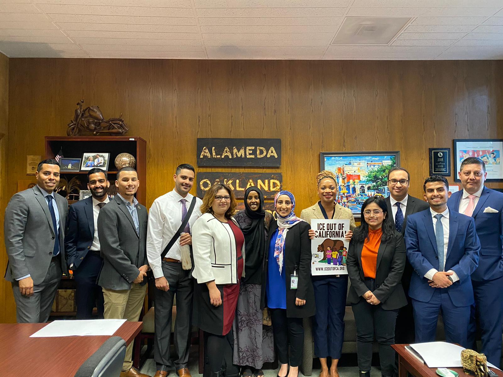 12 community members pose in a elected official's office in Alameda county, gathering to advocate for an end to the JTTF.