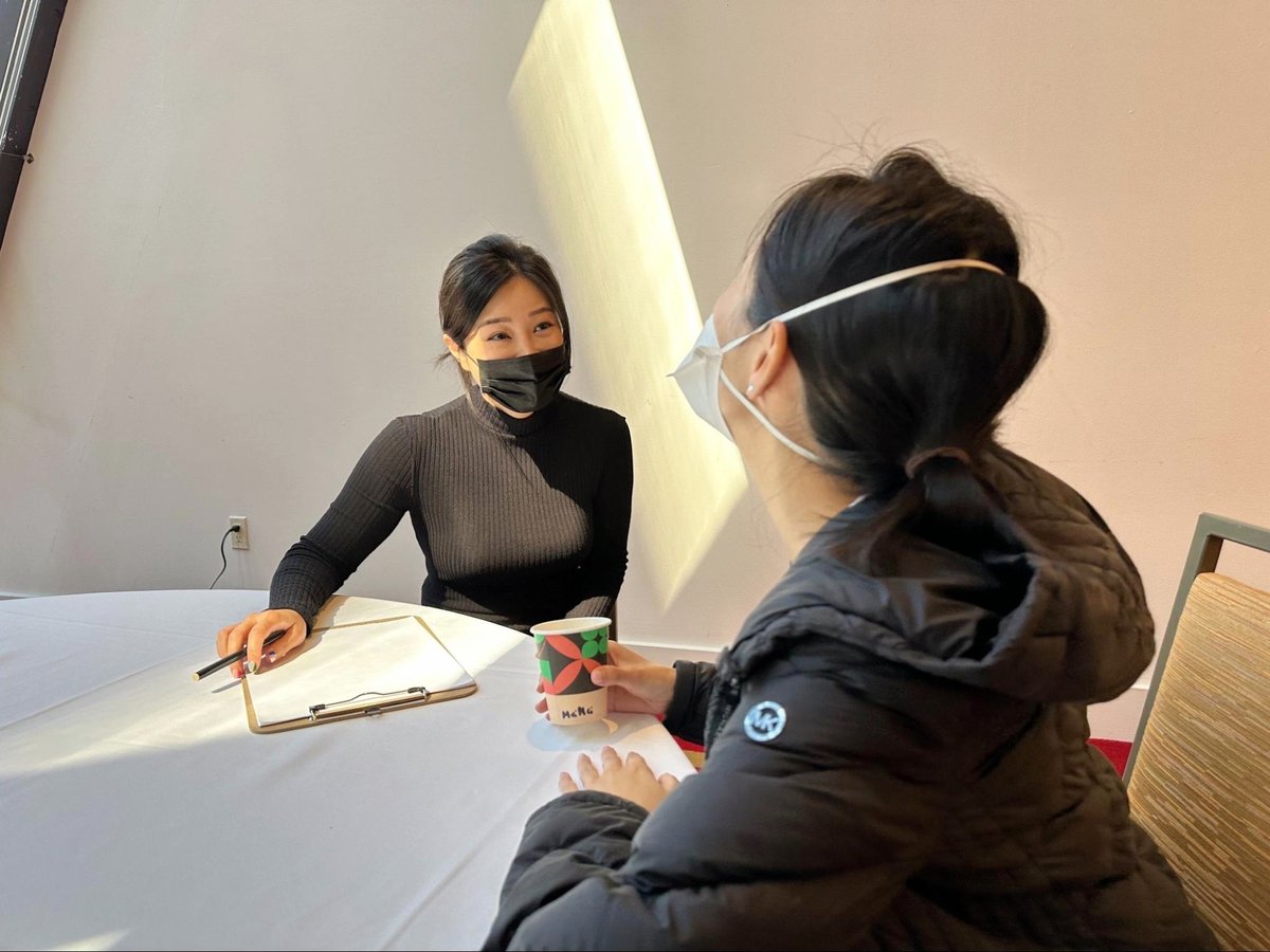 Sallie and Mei Mei sit at a table in conversation.