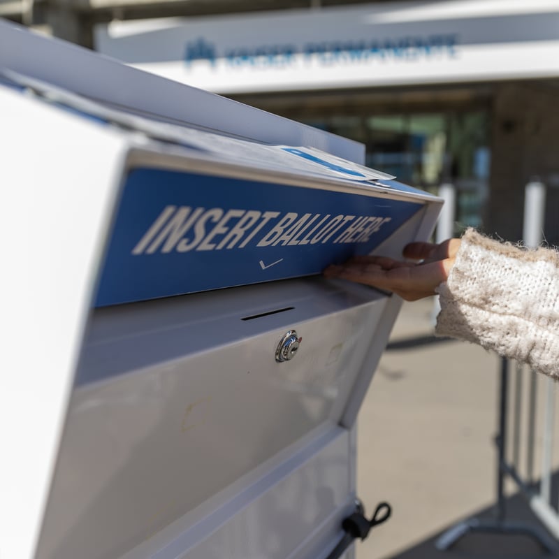 A ballot box with the text 'Insert Ballot Here' being opened.
