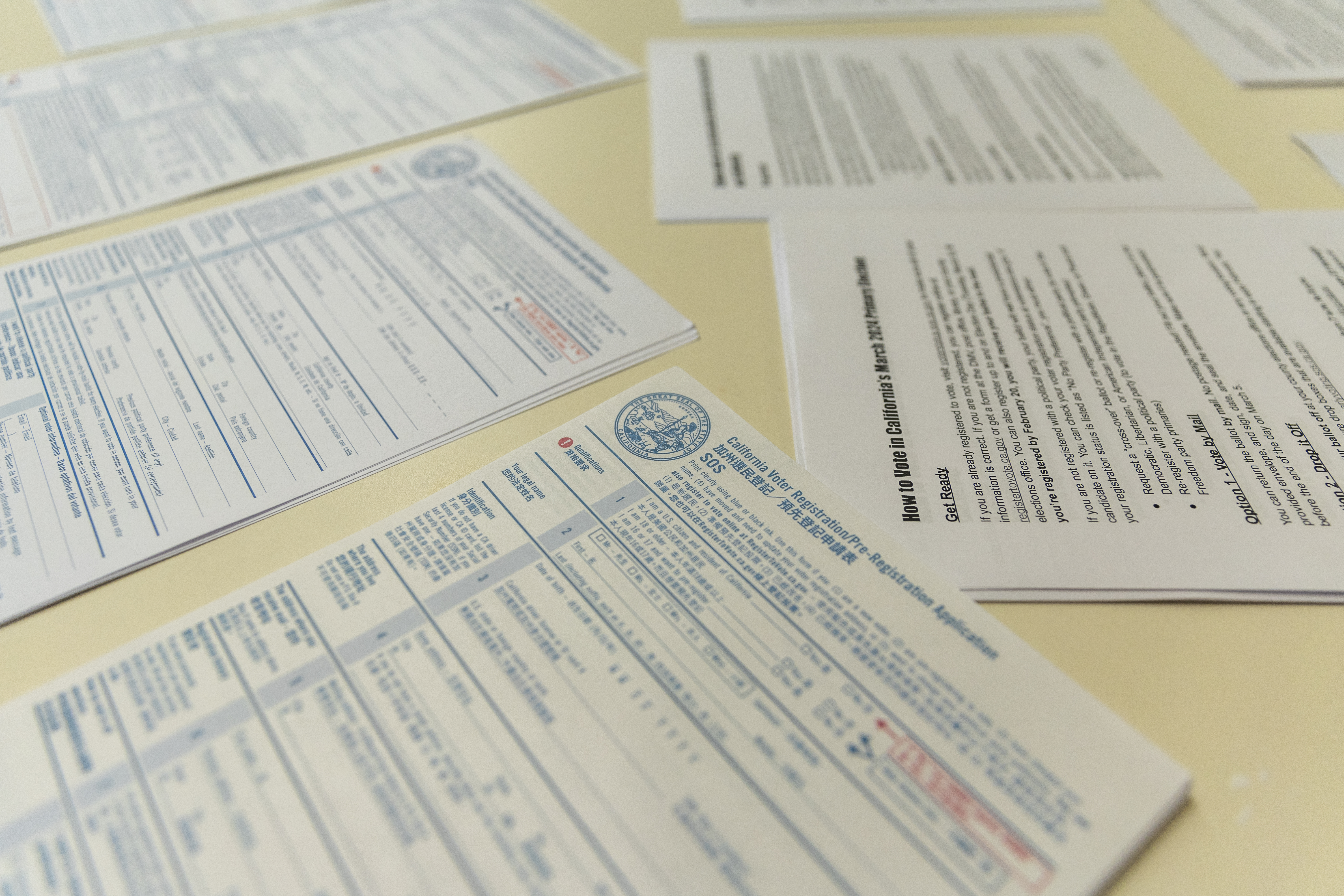 Voter registration forms and other materials spread out on a desk.