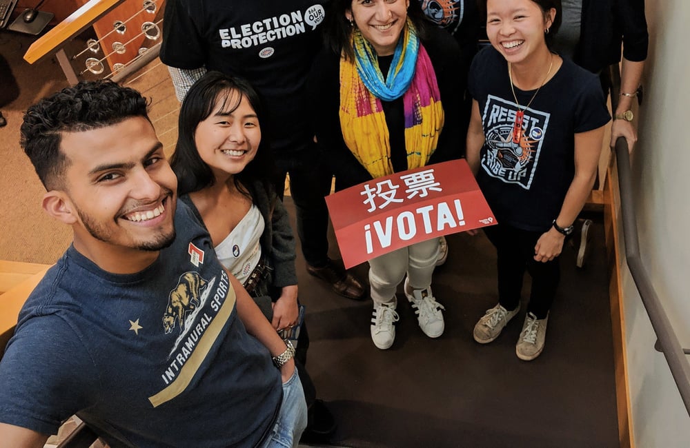 Six people stand on stairs holding voting signs and wearing Asian Law Caucus tshirts