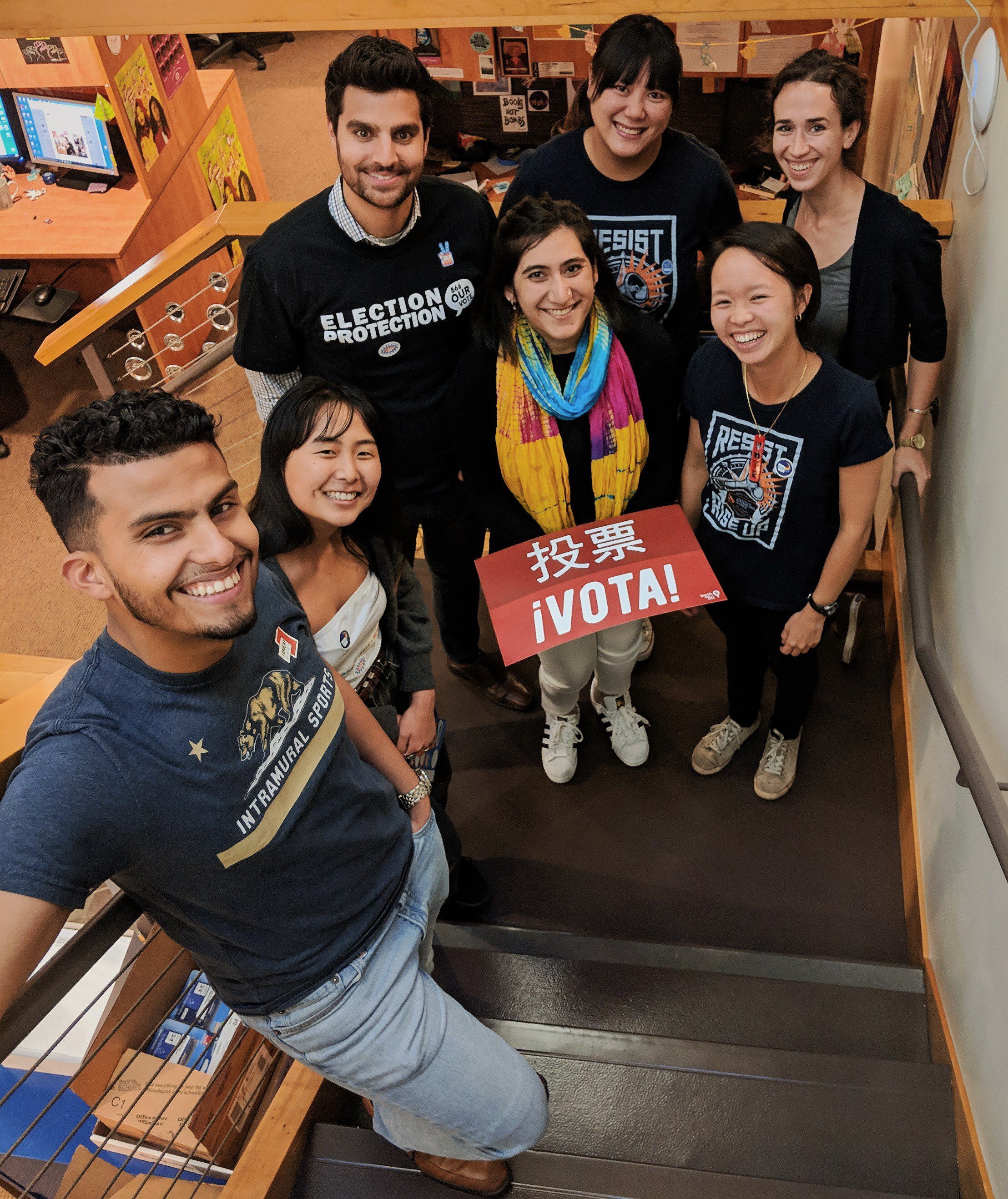 Six people stand on stairs holding voting signs and wearing Asian Law Caucus tshirts