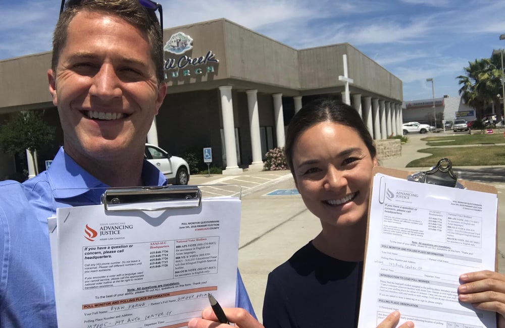 Two people hold up clipboards with poll monitoring information