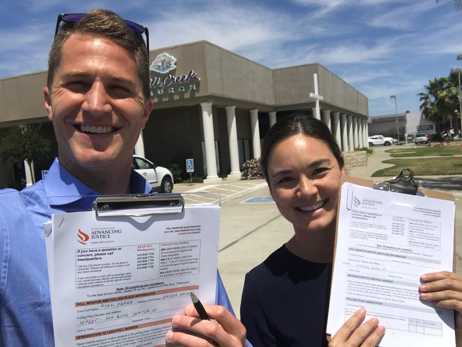 Two people hold up clipboards with poll monitoring information