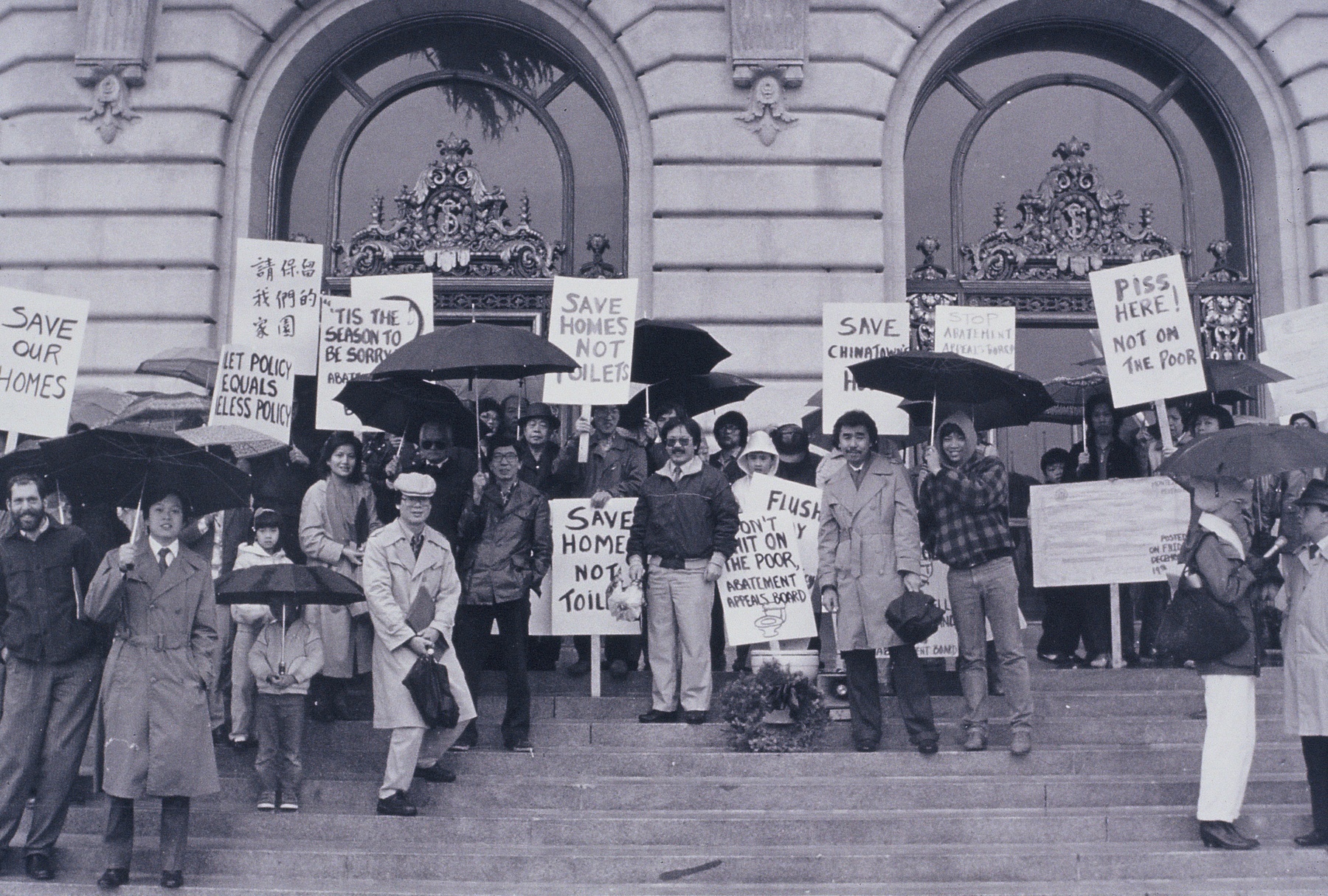 Black and white photo of protestors standing on the steps in front of San Francisco City Hall holding signs