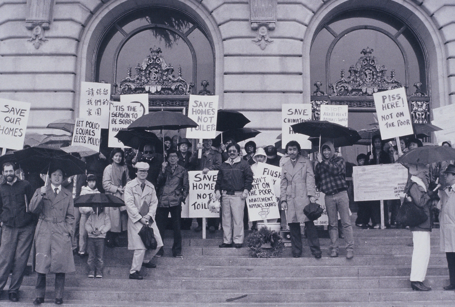 Black and white photo of protestors standing on the steps in front of San Francisco City Hall holding signs