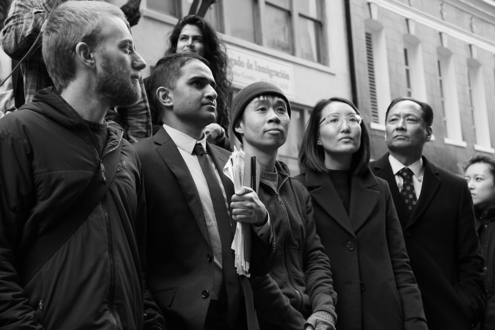 Black and white photo of 4 men and one woman outside standing in a row looking up