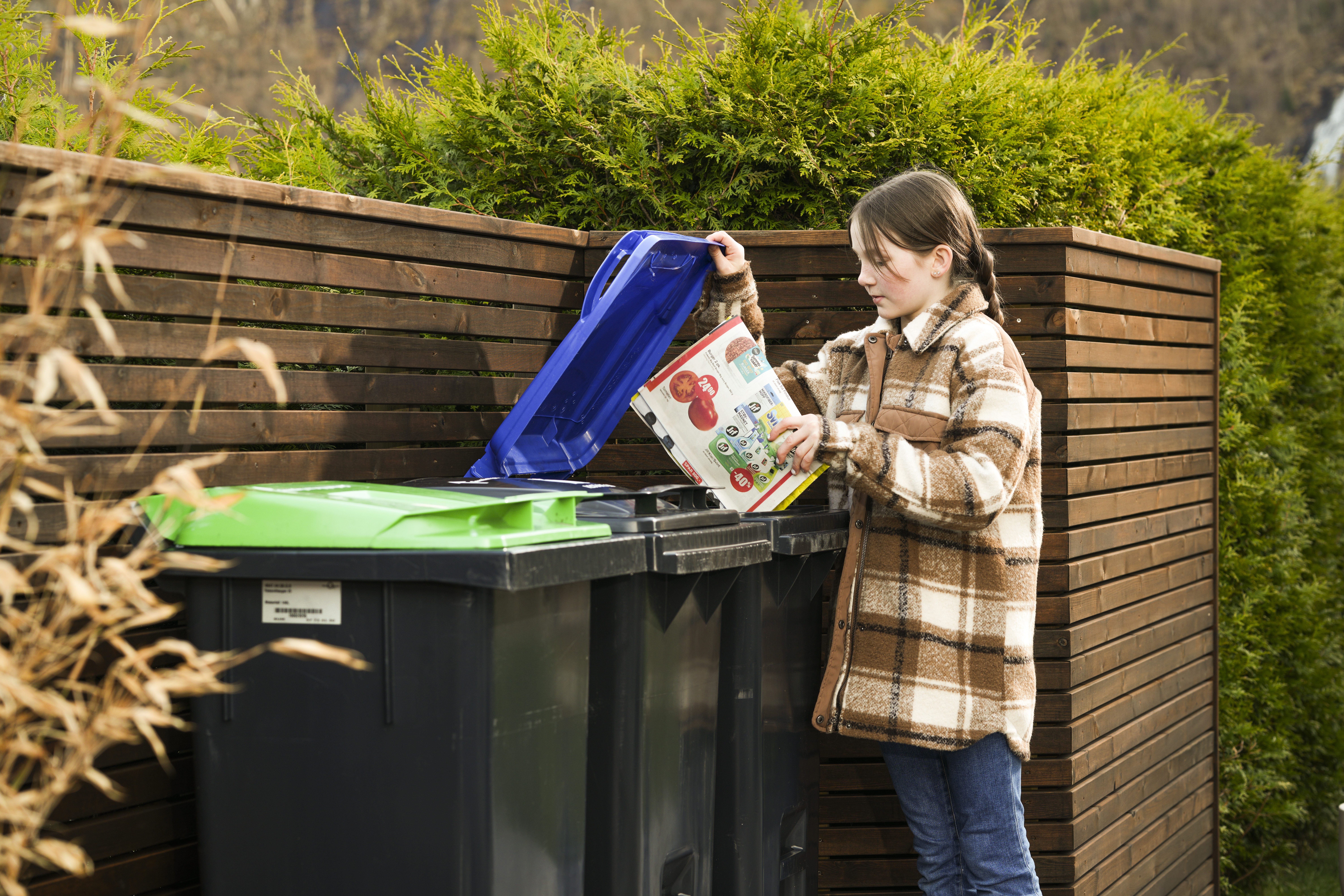 Bilde av jente som kaster ein pappkartong i avfallsdunk.