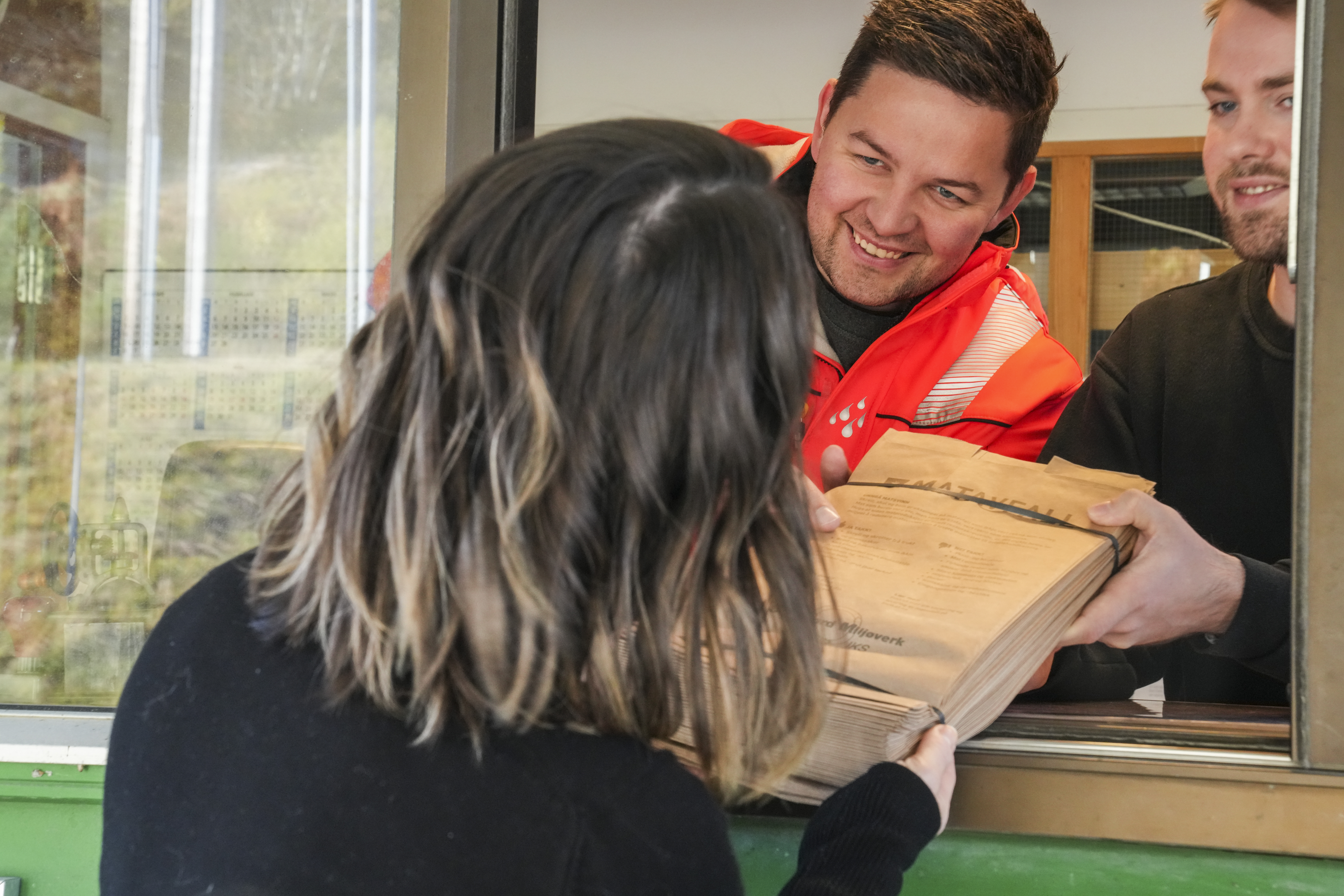 Bilde av kunde som får papirposer for matavfall gjennom luke.