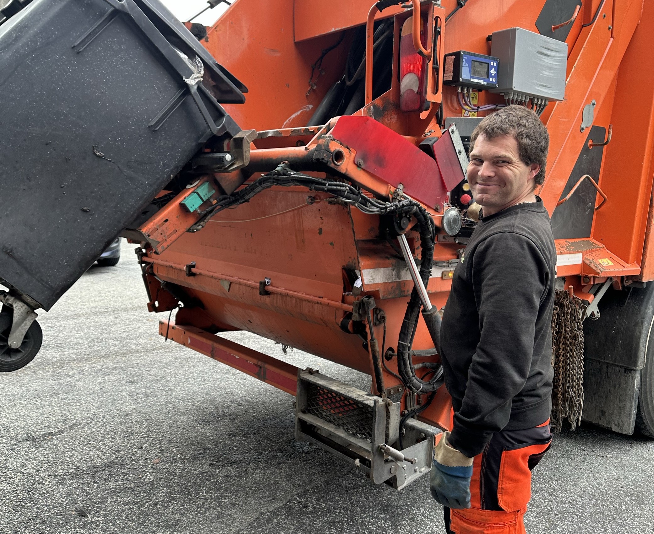 Renovatør som tømmer avfall i renovasjonsbil