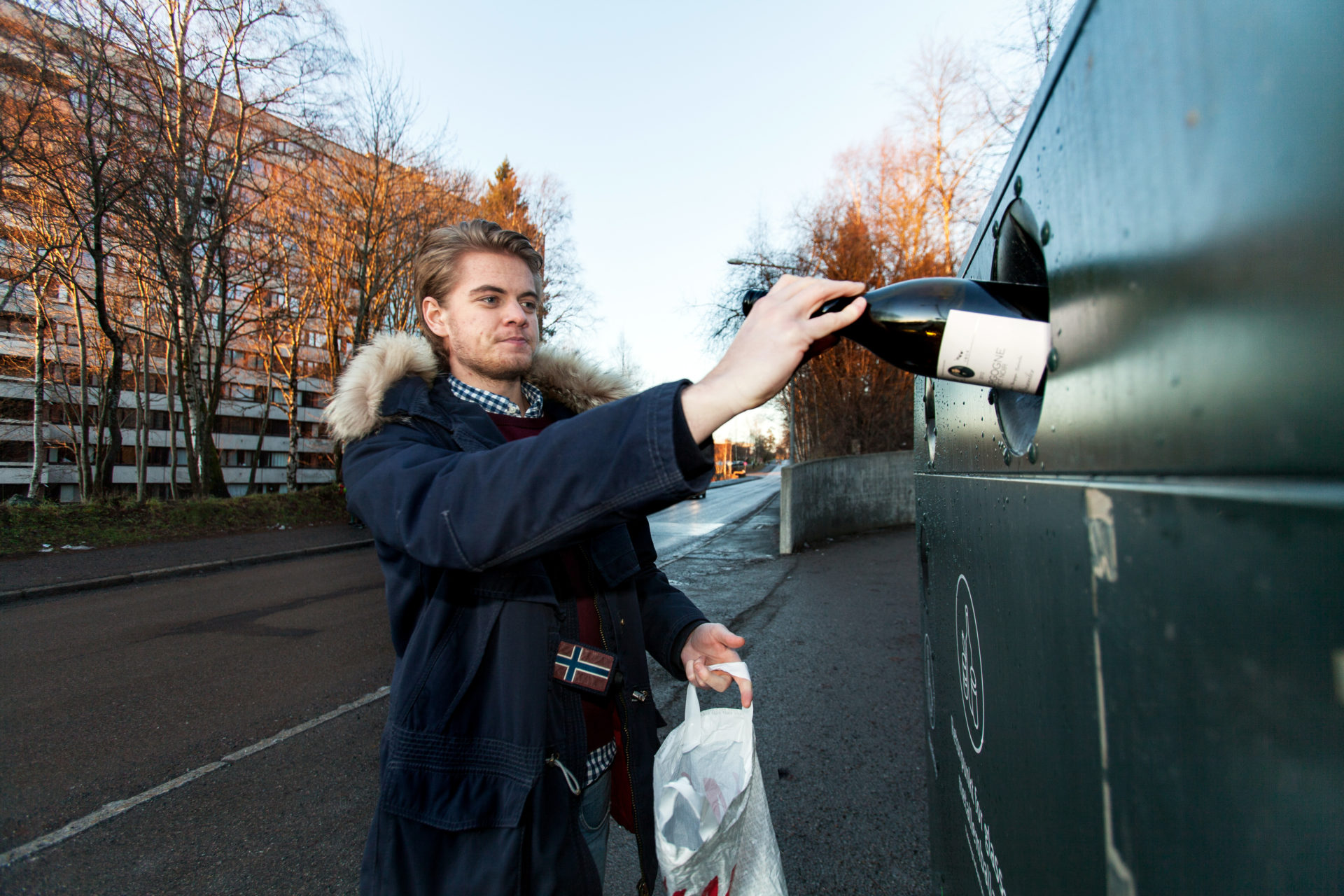 Ung mann sorterer glass- og metallemballasje på returpunkt
