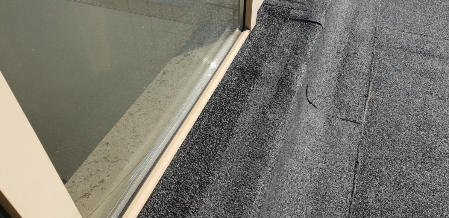 Grey carpet edge meets white skirting board and green wall, showing corner junction of flooring and wall materials.