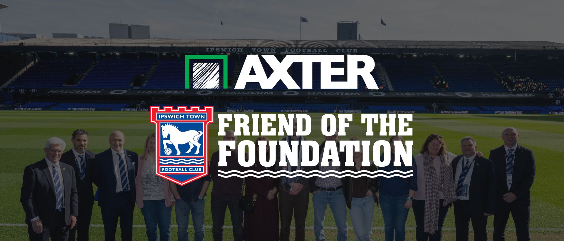 Axter named Friend of the Foundation by Ipswich Town FC, with a group of people standing on the pitch at Portman Road stadium.