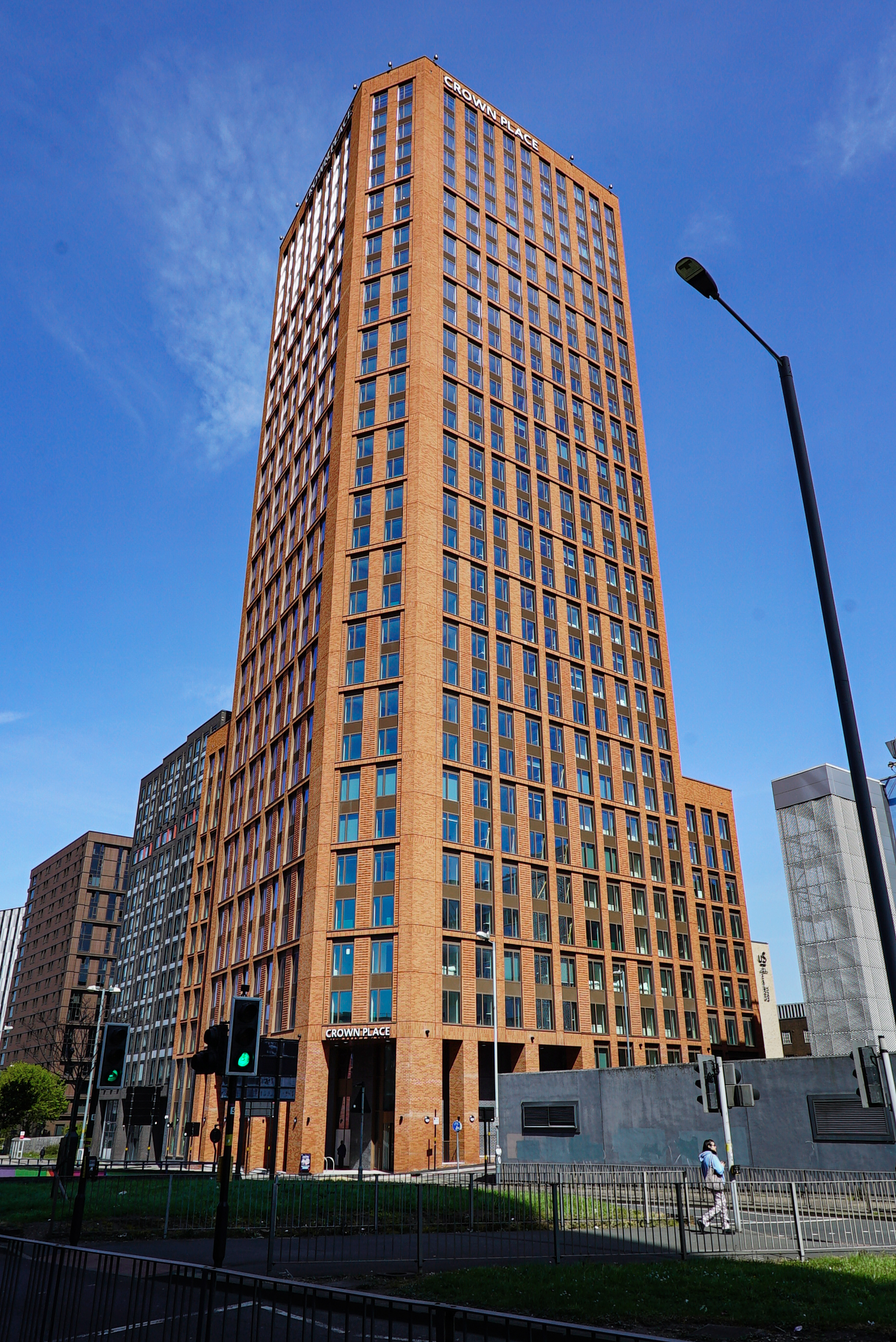 Crown Place, a tall red-brick tower block in Liverpool, photographed from street level against a clear blue sky.