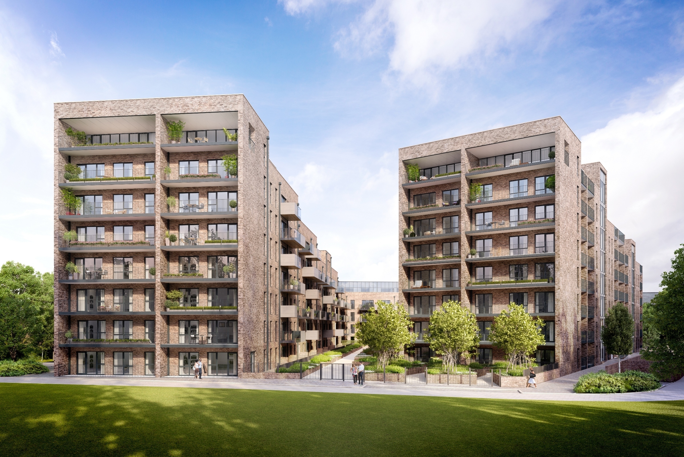 Modern brick apartment blocks with balconies and large windows, surrounded by landscaped green space and trees under cloudy sky.