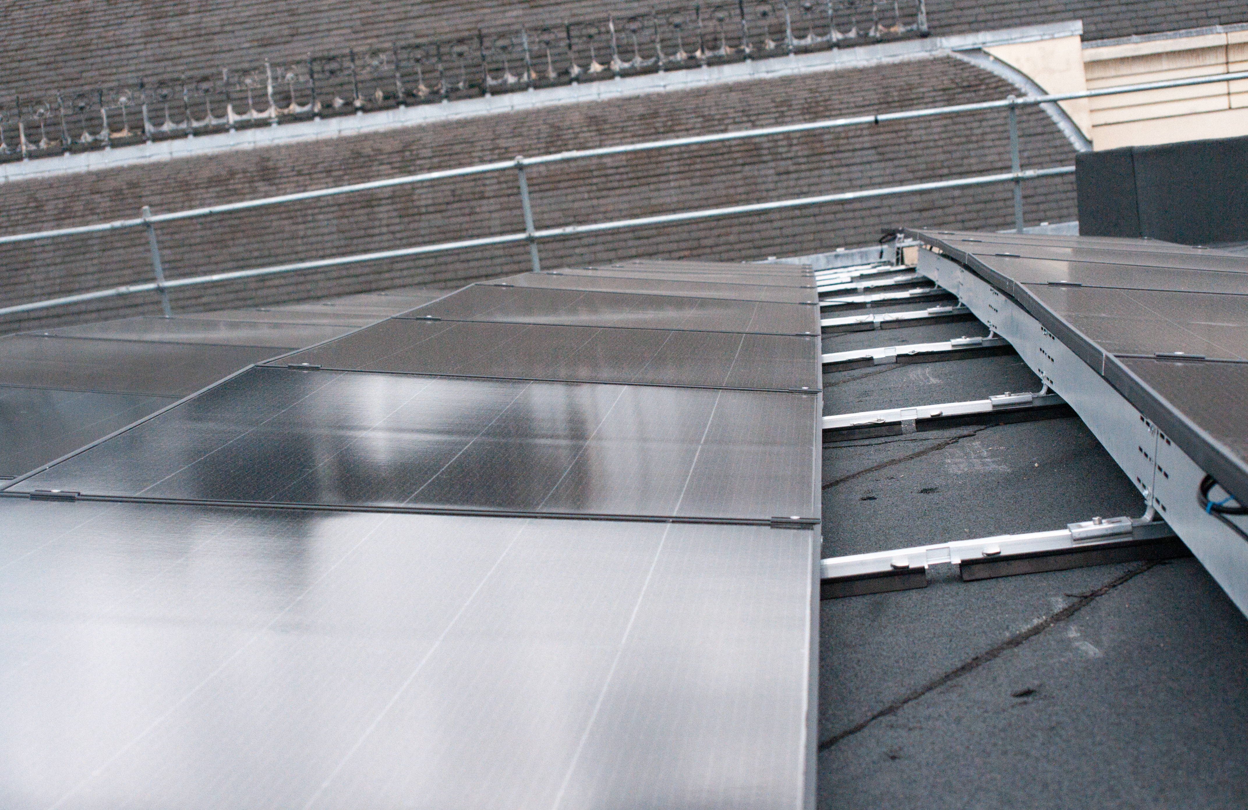 Wet concrete steps and metal handrail on grey stadium or arena seating with water pooling on surfaces.