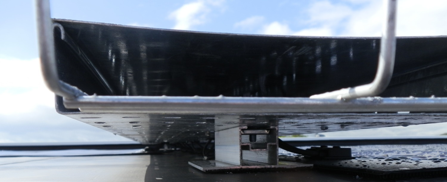 Black-hulled boat with white trim lifted on boat lift above water, blue sky with white clouds in background.