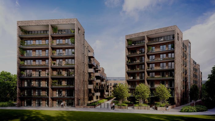 Modern grey brick residential buildings with multiple storeys, glass balconies, and landscaped green spaces under blue sky.