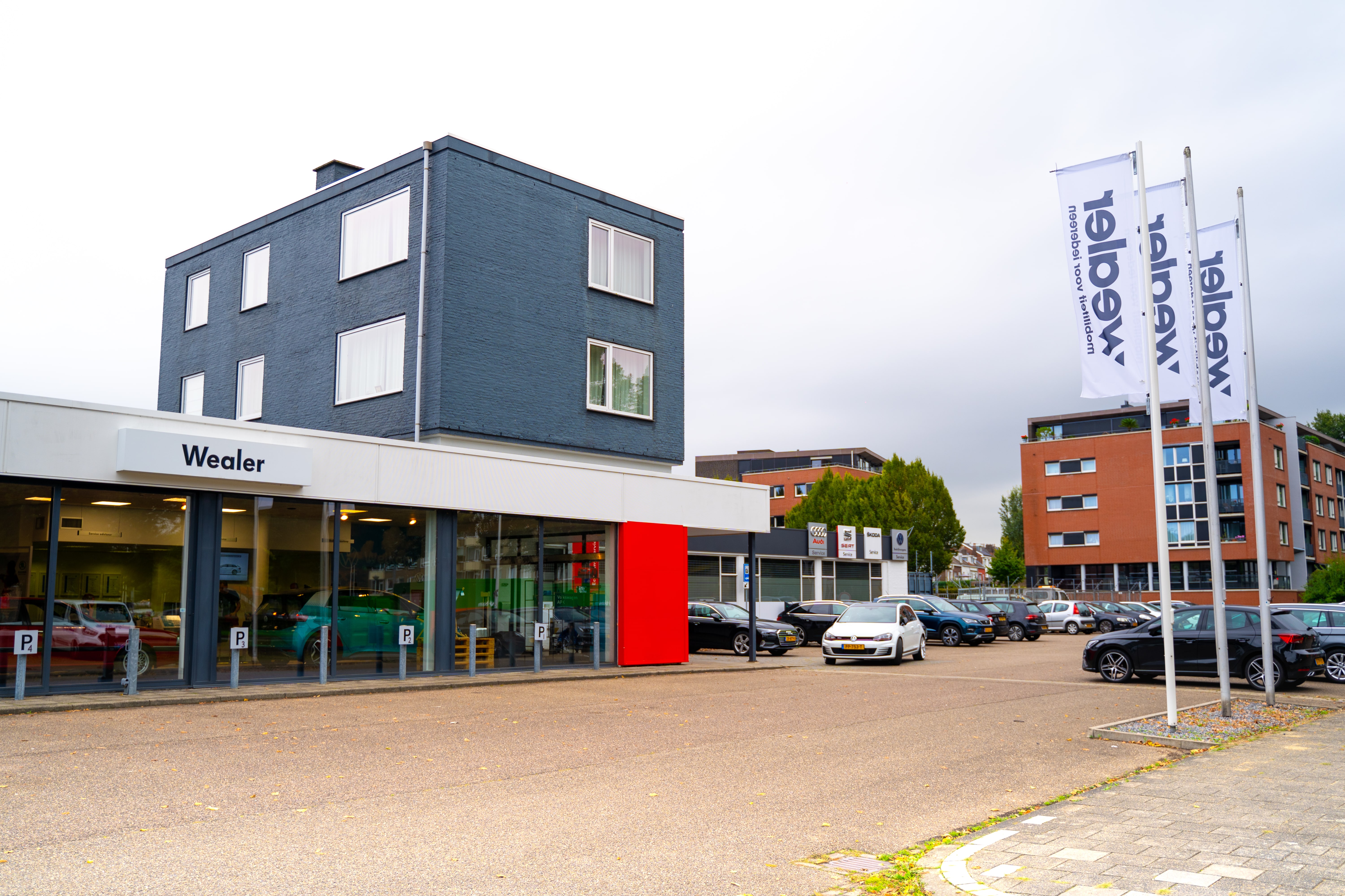 Drie vlaggen voor gebouw met rode muur.