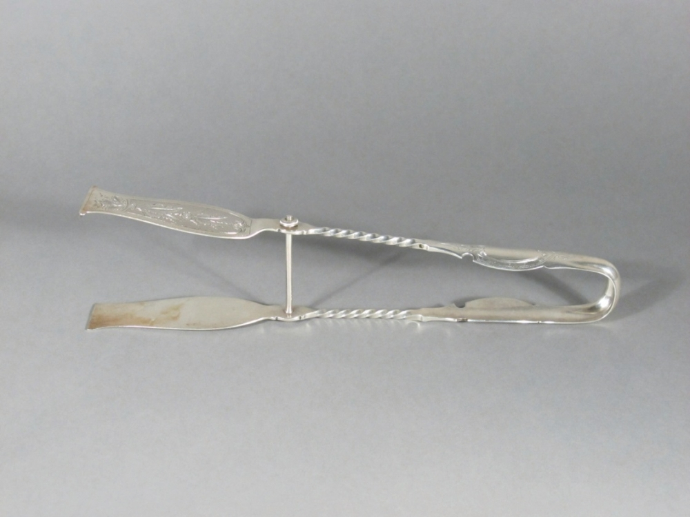 Silver-plated antique tongs with ornate handles and a twisted shaft, designed for delicate tasks, resting against a plain gray background.