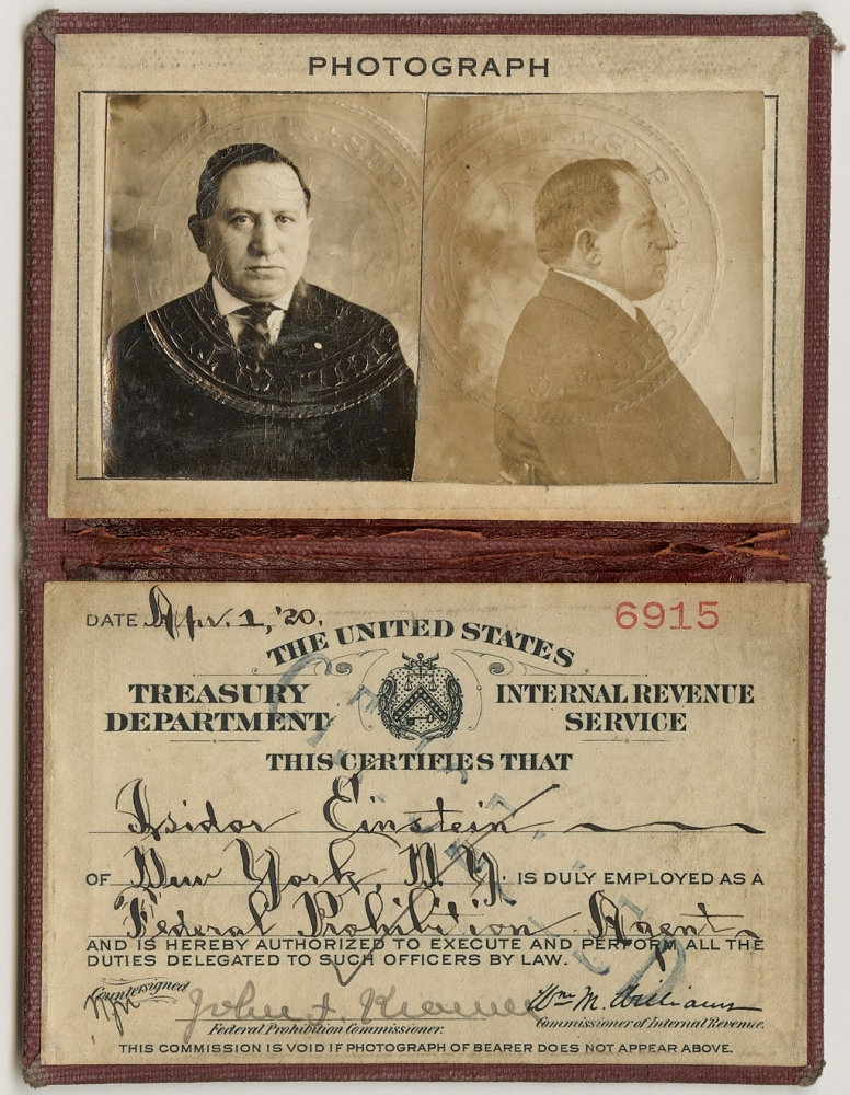 An old identification card featuring a black and white portrait of a man facing forward and in profile. The card is dated April 1, 1920, for the United States Treasury Department Internal Revenue Service with signatures and a seal.