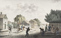 Historical illustration of a street scene with enslaved individuals working, a man on horseback, and people walking or observing. Wooden buildings and trees are in the background.