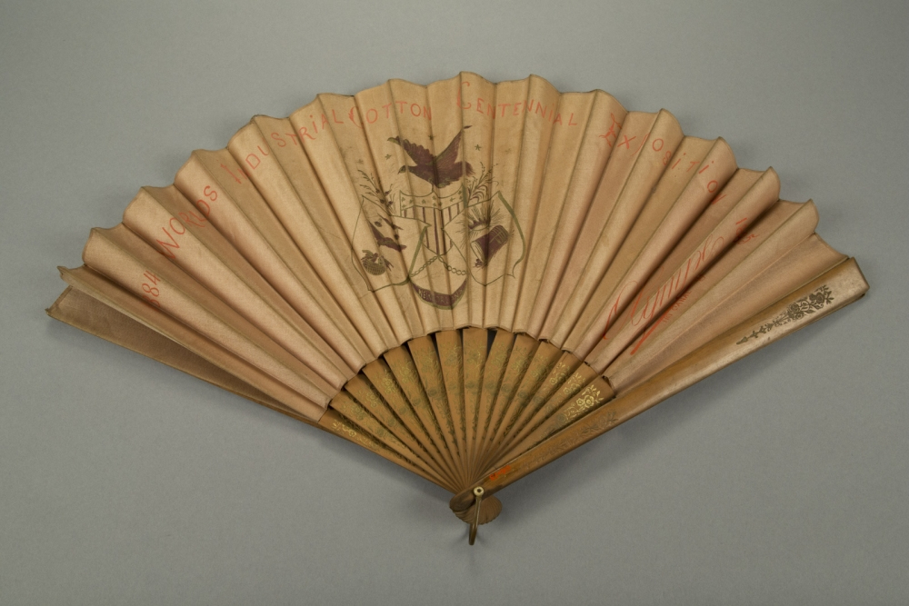A vintage paper fan with a colorful design featuring a bird and a shield. Text on the fan reads BRYAN & COLT INDUSTRIAL EXPOSITION CENTENNIAL. The fan is open against a plain background.