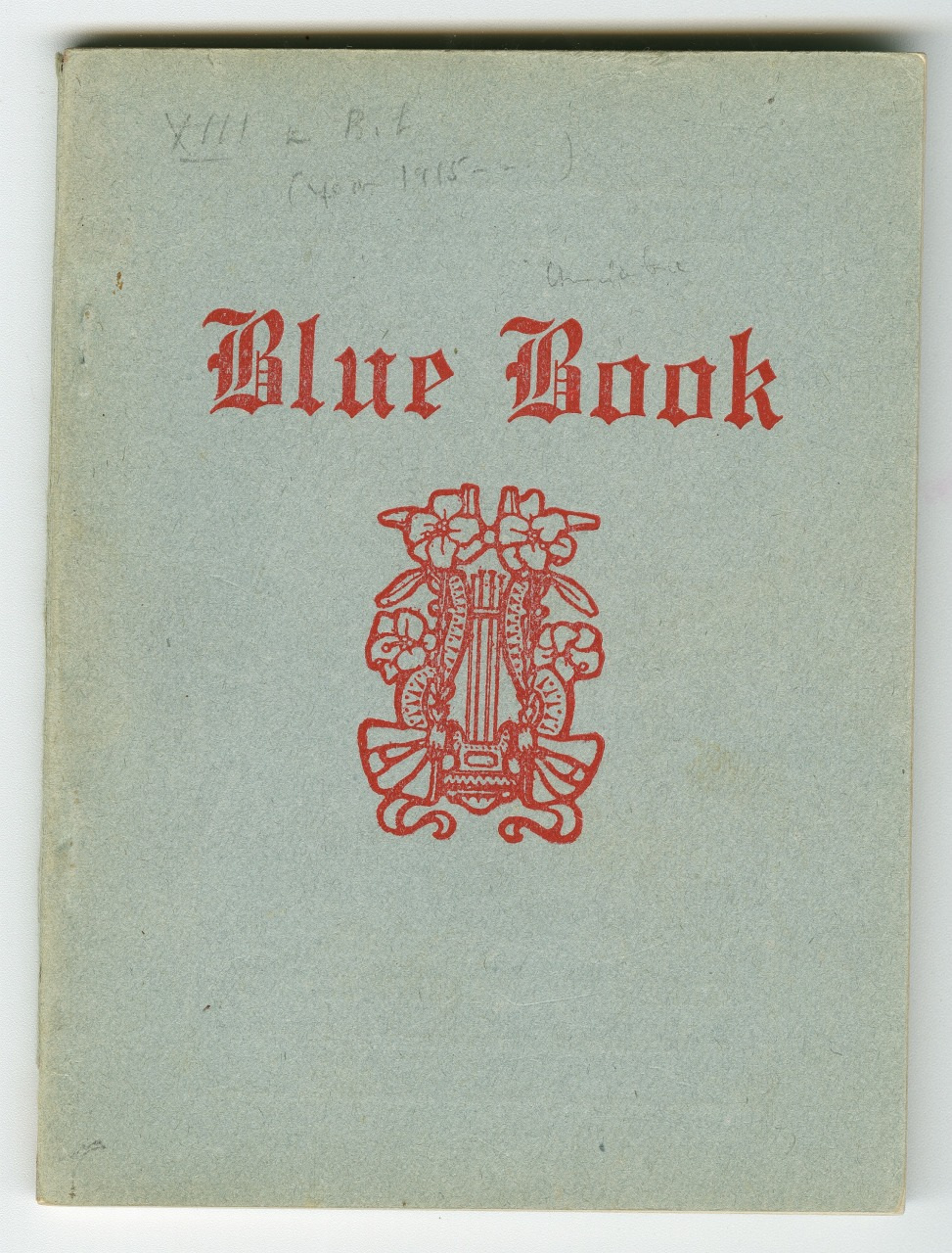 A vintage book cover titled Blue Book in red text on a blue-gray background, featuring an ornate red emblem with floral and decorative elements. Handwritten notes are faintly visible at the top.