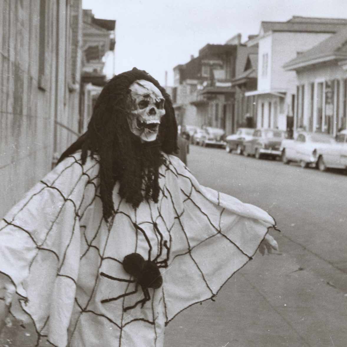 A person costumed in a skull mask and a spider web shawl in the French Quarter.