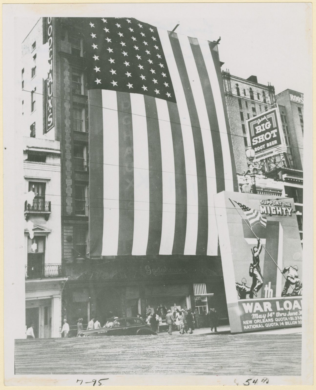 A black and white photo shows a massive American flag draped over the front of Godchaux’s department store during World War II.