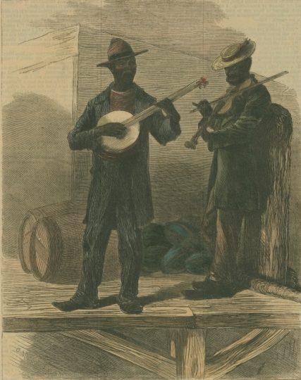 Two men stand on a wooden platform. One plays a banjo, wearing a hat and suit. The other holds a violin under his arm, wearing a different style of hat. Barrels are visible in the background, and clothing or bags are piled behind them.