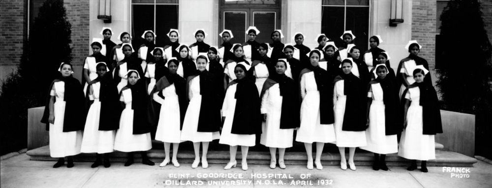 A historic black-and-white photograph showing a group of nurses in uniform, possibly from the Flint-Goodridge Hospital of Dillard University, posing in front of a building in April 1932. The women are wearing white dresses and dark capes.