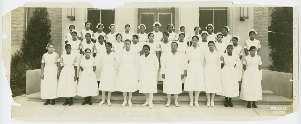A group of women in white uniforms and caps, standing in rows, pose for a photo in front of a building marked Dillard University School of Nursing, 1932.