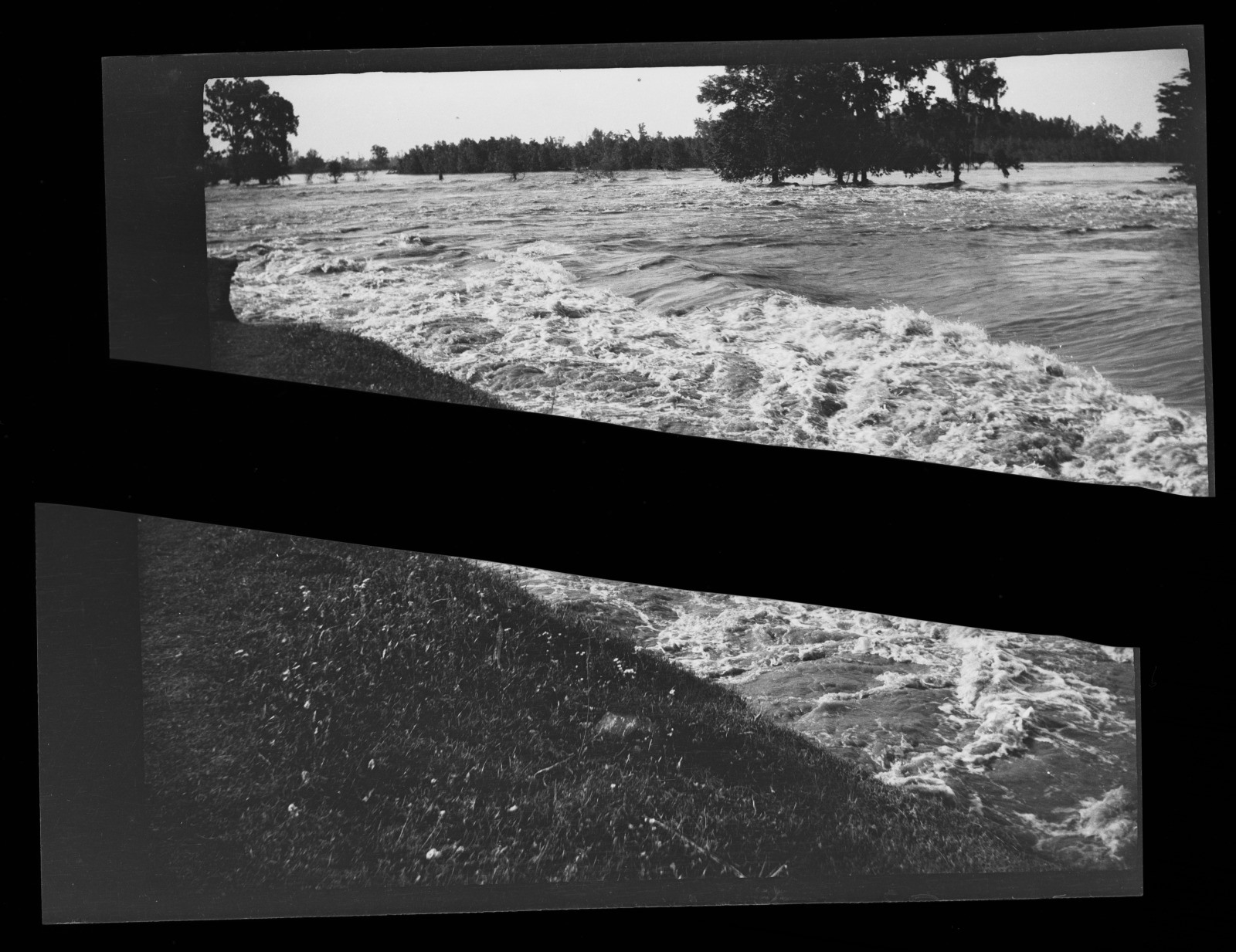 A black and white photograph shows a flooded river with turbulent waters overflowing onto a grassy bank. Trees are partially submerged in the background, indicating the severity of the flooding.