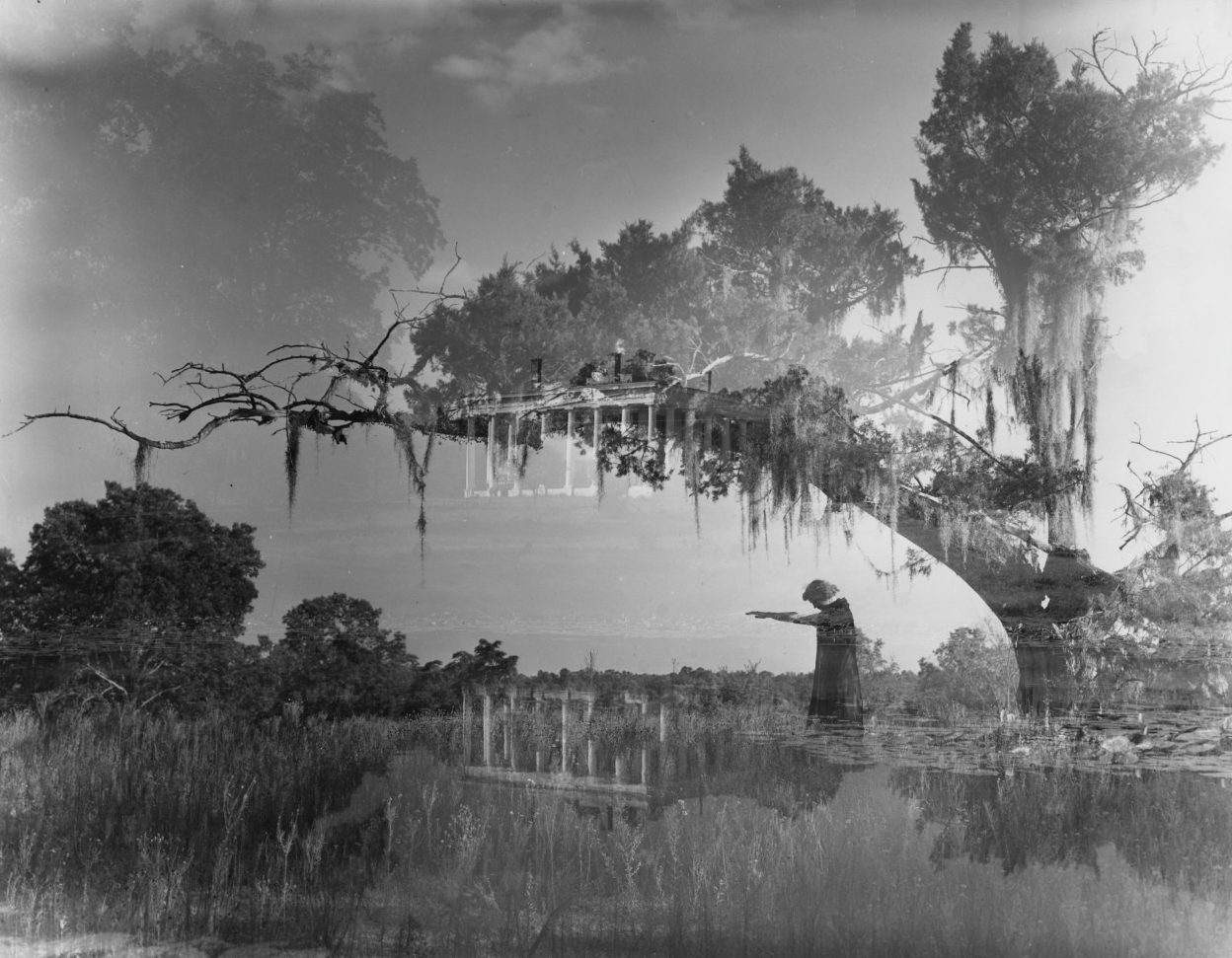 A black and white double exposure image featuring a landscape with trees and a person standing on a path, pointing. The overlay includes a classical building with columns. Moss hangs from the trees, creating an atmospheric effect.