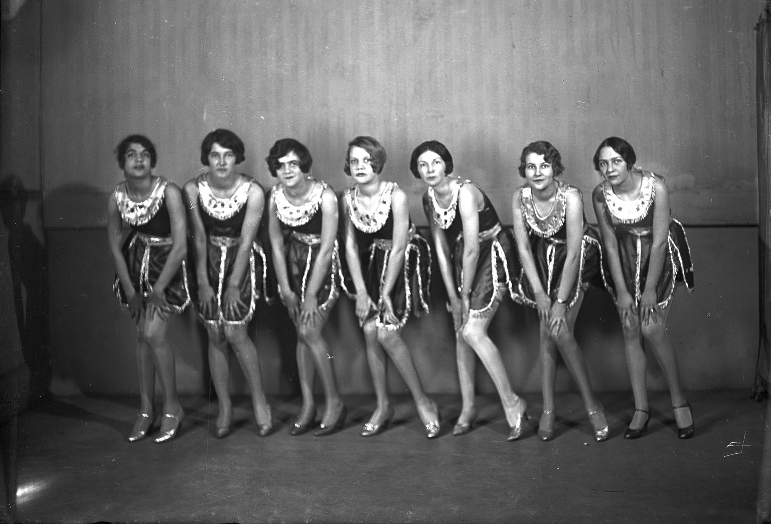 A black and white photo of seven women in flapper costumes, between 1929 and 1940.