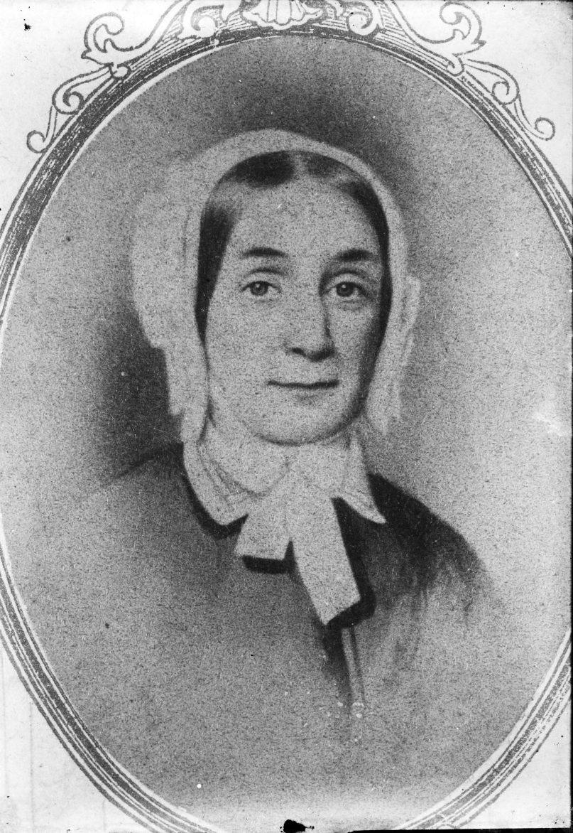 A black-and-white oval portrait of a woman wearing a bonnet and a simple dress with a bow at the neck. She appears to be from the 19th century. The background is plain, and the portrait has an ornate border.