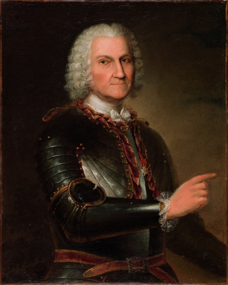A historical portrait of a man with white curly hair wearing a dark metallic armor and a deep red sash. He is gesturing with his right hand, looking directly ahead, set against a dark background.