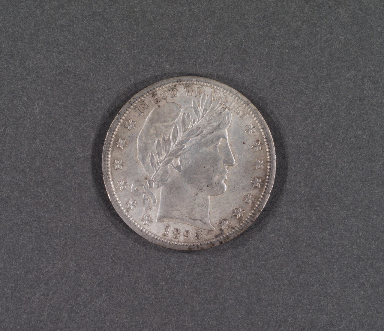 A silver coin featuring a profile of a person wearing a laurel wreath, surrounded by 13 stars. The date 1895 is visible at the bottom. The coin is set against a plain, dark background.